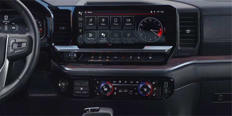 Close-up of a car's dashboard with a navigation screen displaying apps like Audio, Maps, Phone, and Google Assistant.