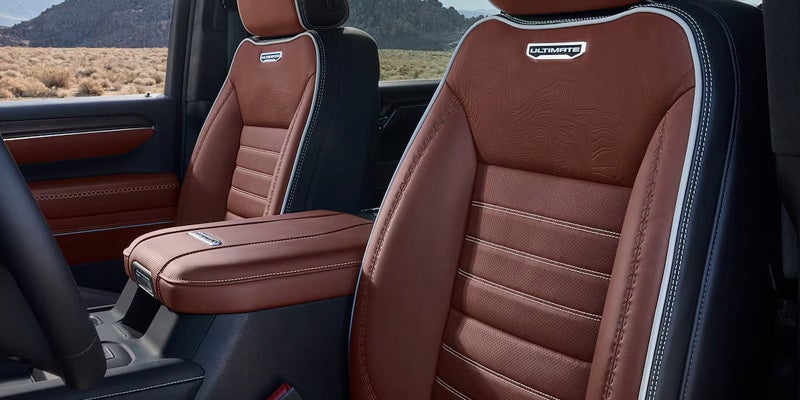 Interior view of a vehicle showing brown leather seats with white stitching and an "ULTIMATE" badge.